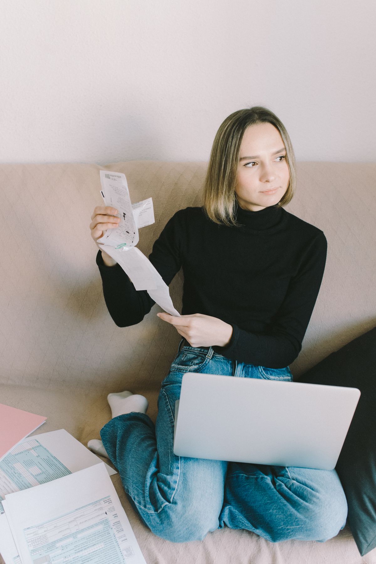 A young person working through their budget on a laptop at the kitchen table