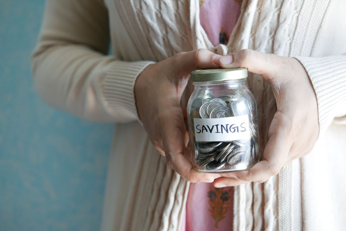 Coins and savings building up in a jar, representing a young adult's emergency fund
